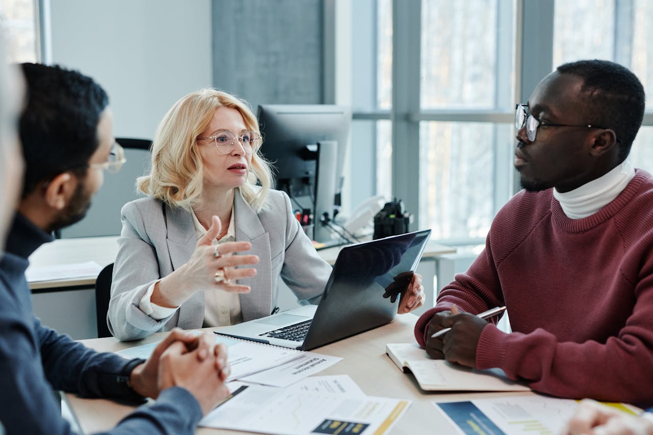 about-us Business professionals discussing strategy around a table with a laptop in an office setting.